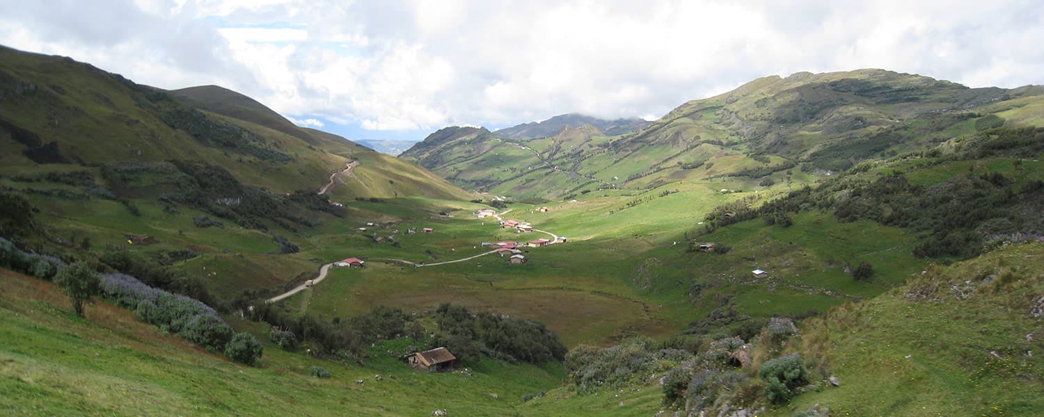 Green valley in the Peruvian Andes at the Conga project area near Cajamarca, with access roads and scattered farm buildings