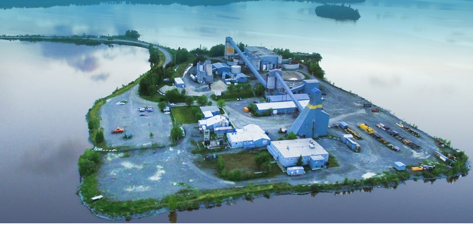 Aerial view of the Kiena Mine site at Val d'Or, Quebec, surrounded by water, with the headframe, conveyors and plant buildings